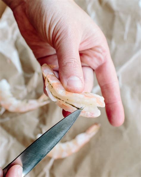 To devein the shrimp and keep the shell on, cut along the back of the shrimp with kitchen shears. Then, use the tip of a paring knife to pull out the vein. The Washington Post.